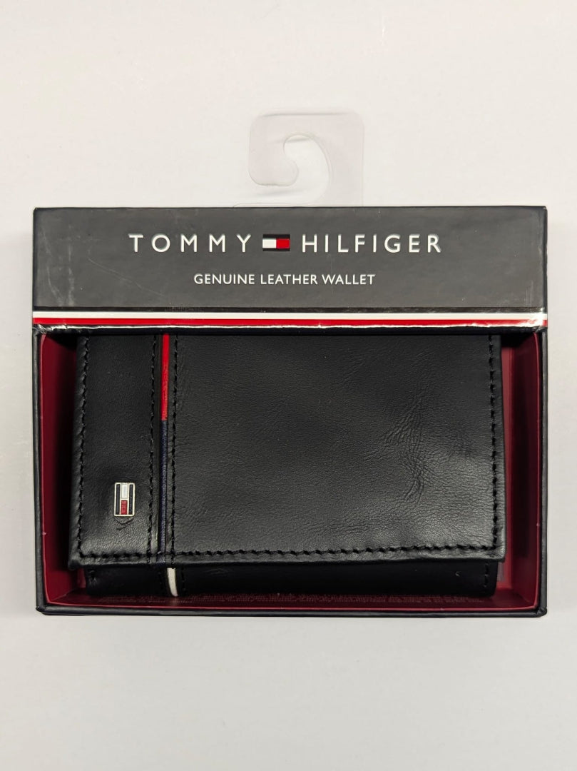 Black leather wallet with red interior in packaging, featuring Tommy Hilfiger branding.