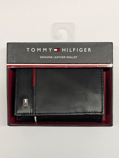 Black leather wallet with red interior in packaging, featuring Tommy Hilfiger branding.