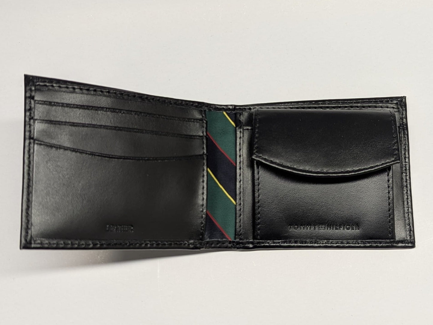Black leather wallet with a striped tie inside on a light gray background