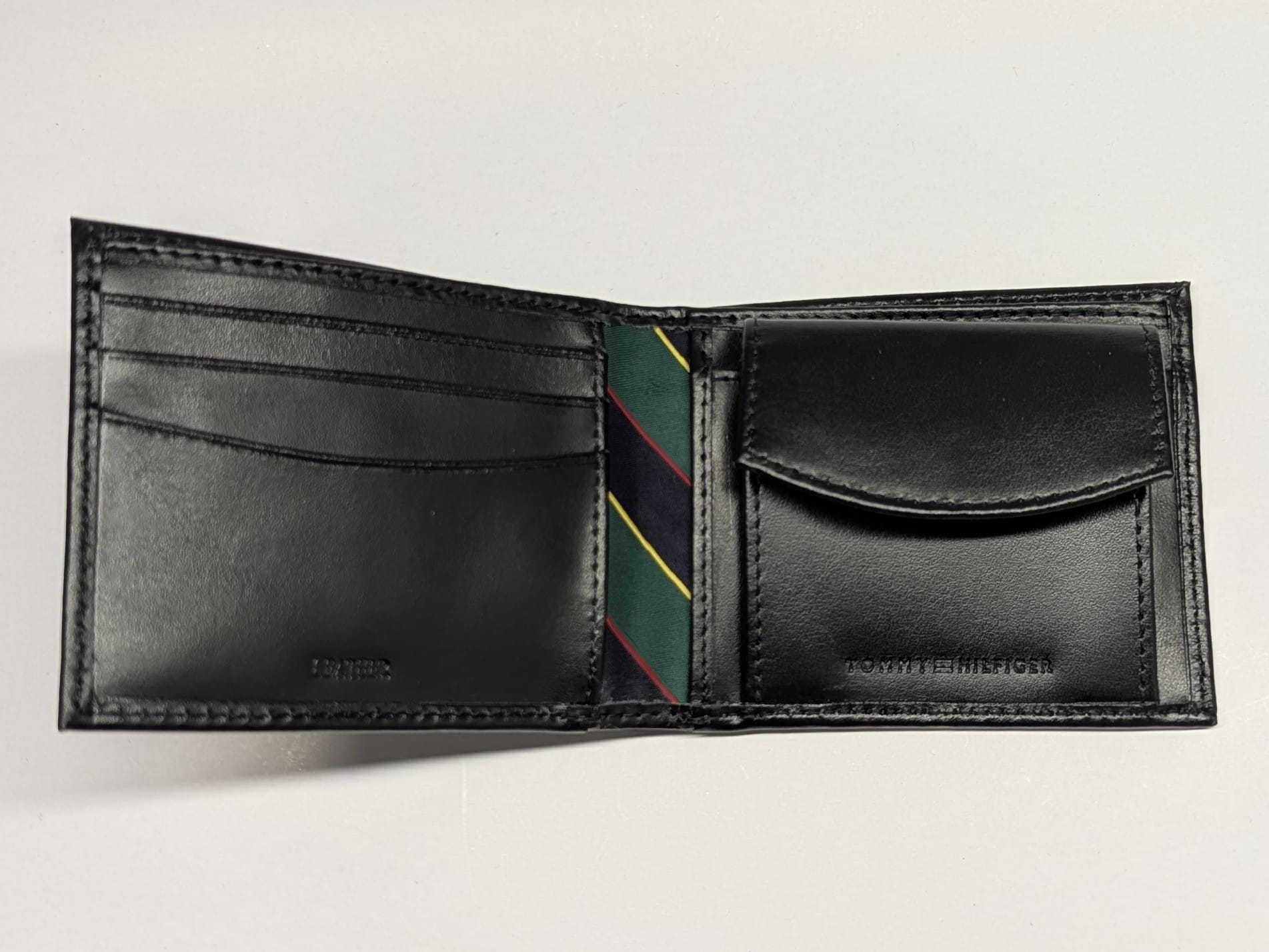 Black leather wallet with a striped tie inside on a light gray background