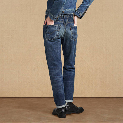 Person wearing a denim jumpsuit against a beige background