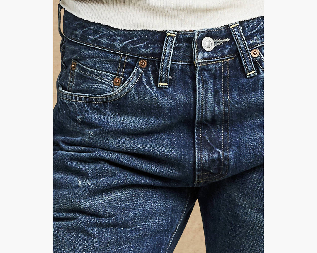 Close-up of blue jeans with a beige background