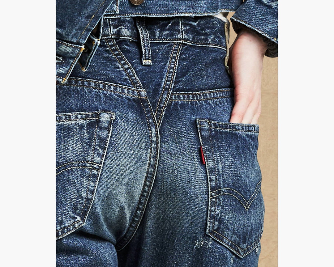 Close-up of blue denim jeans with a brand logo on a white background