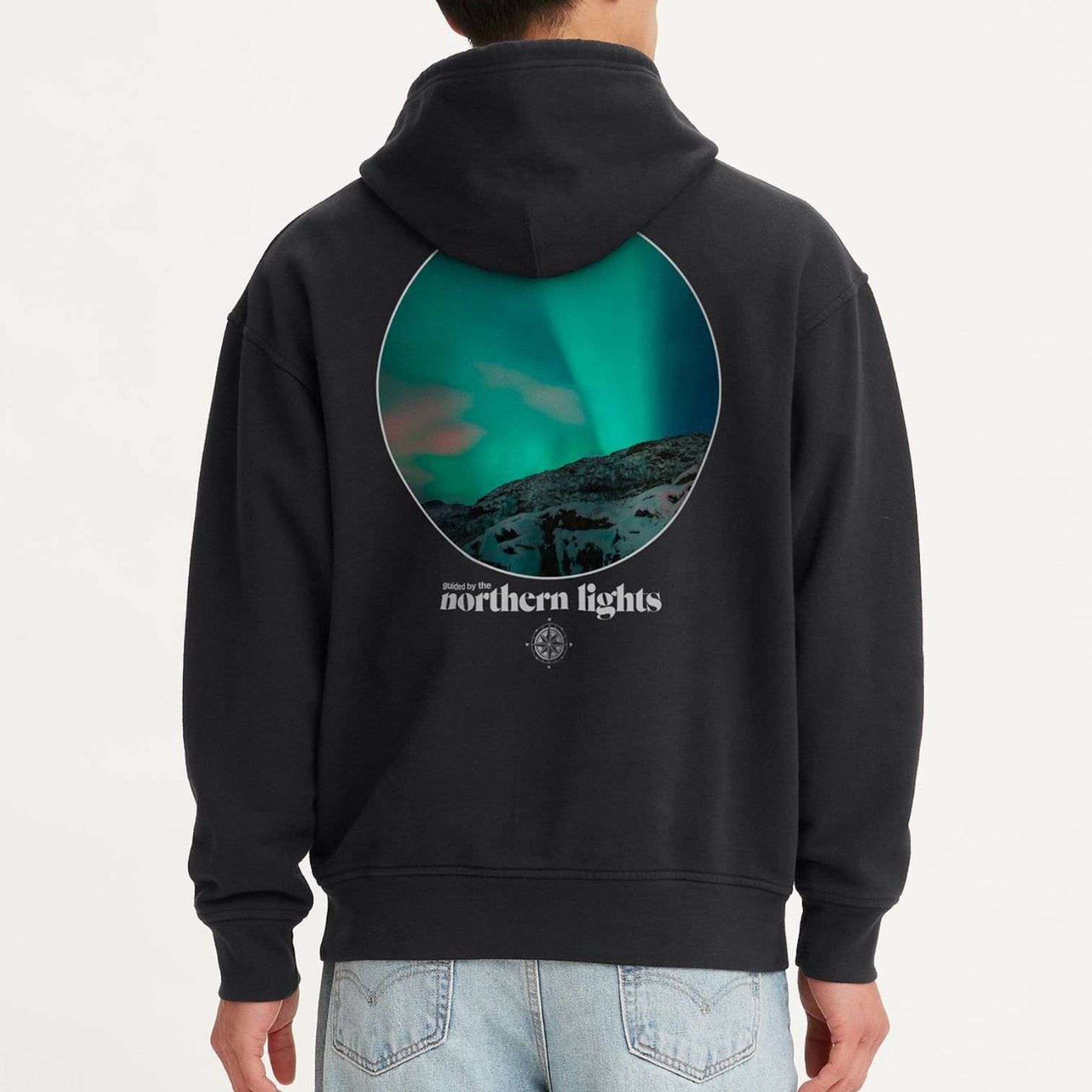 Person wearing a black hoodie with a graphic design on the back against a white background