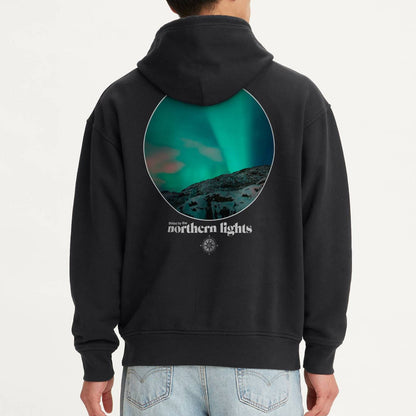 Person wearing a black hoodie with a graphic design on the back against a white background