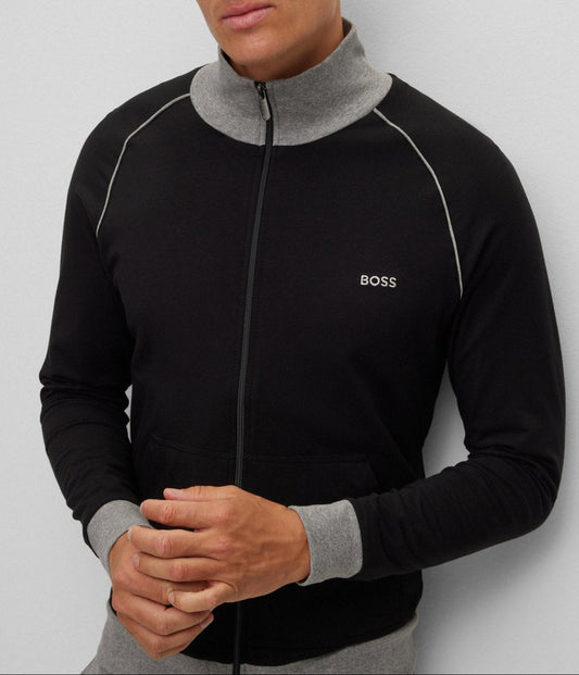 Man wearing a black and gray jacket with a visible brand logo on a light gray background