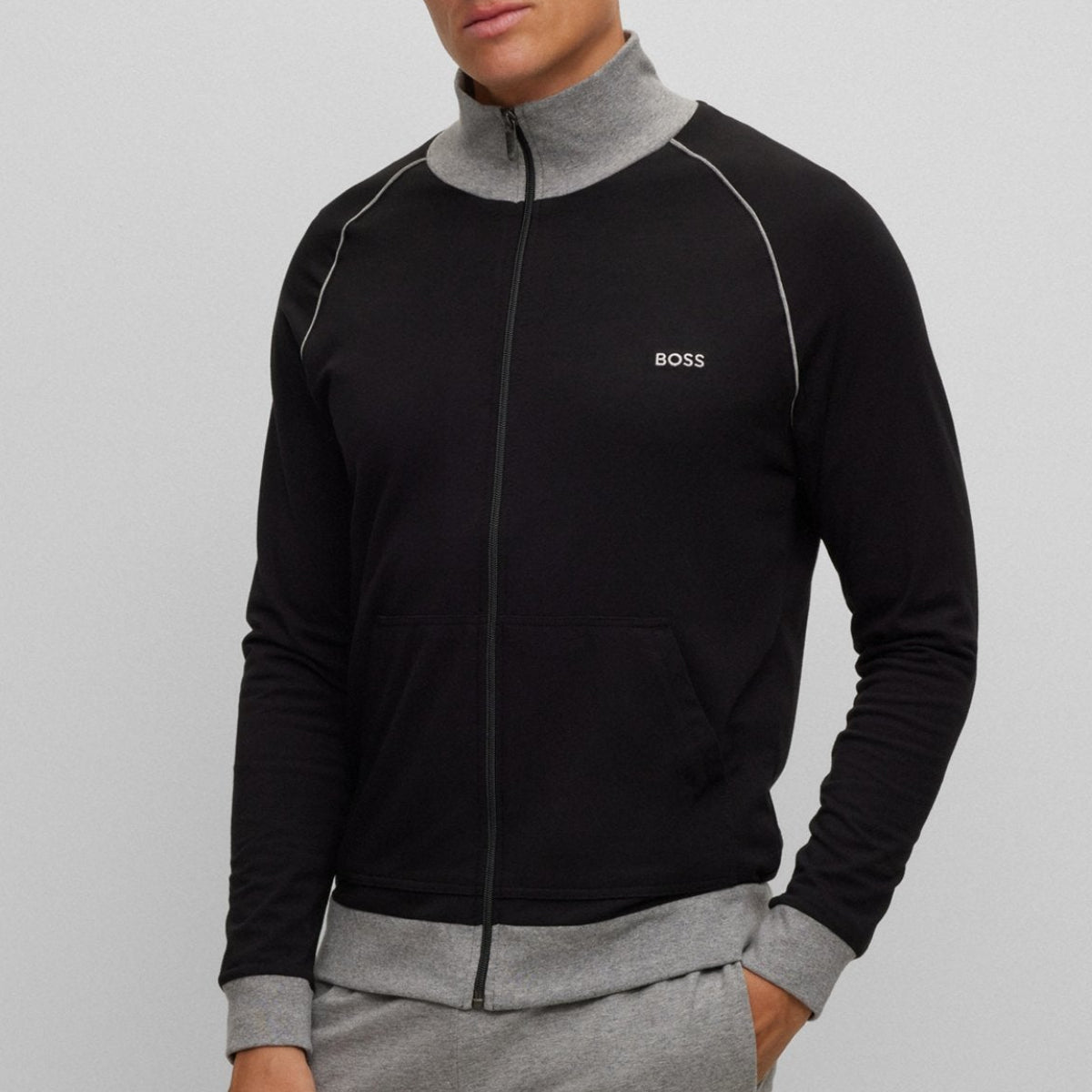 Man wearing a black and gray tracksuit with a visible brand logo on a light gray background