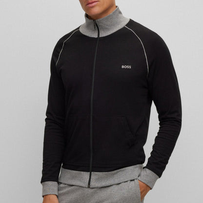 Man wearing a black and gray tracksuit with a visible brand logo on a light gray background