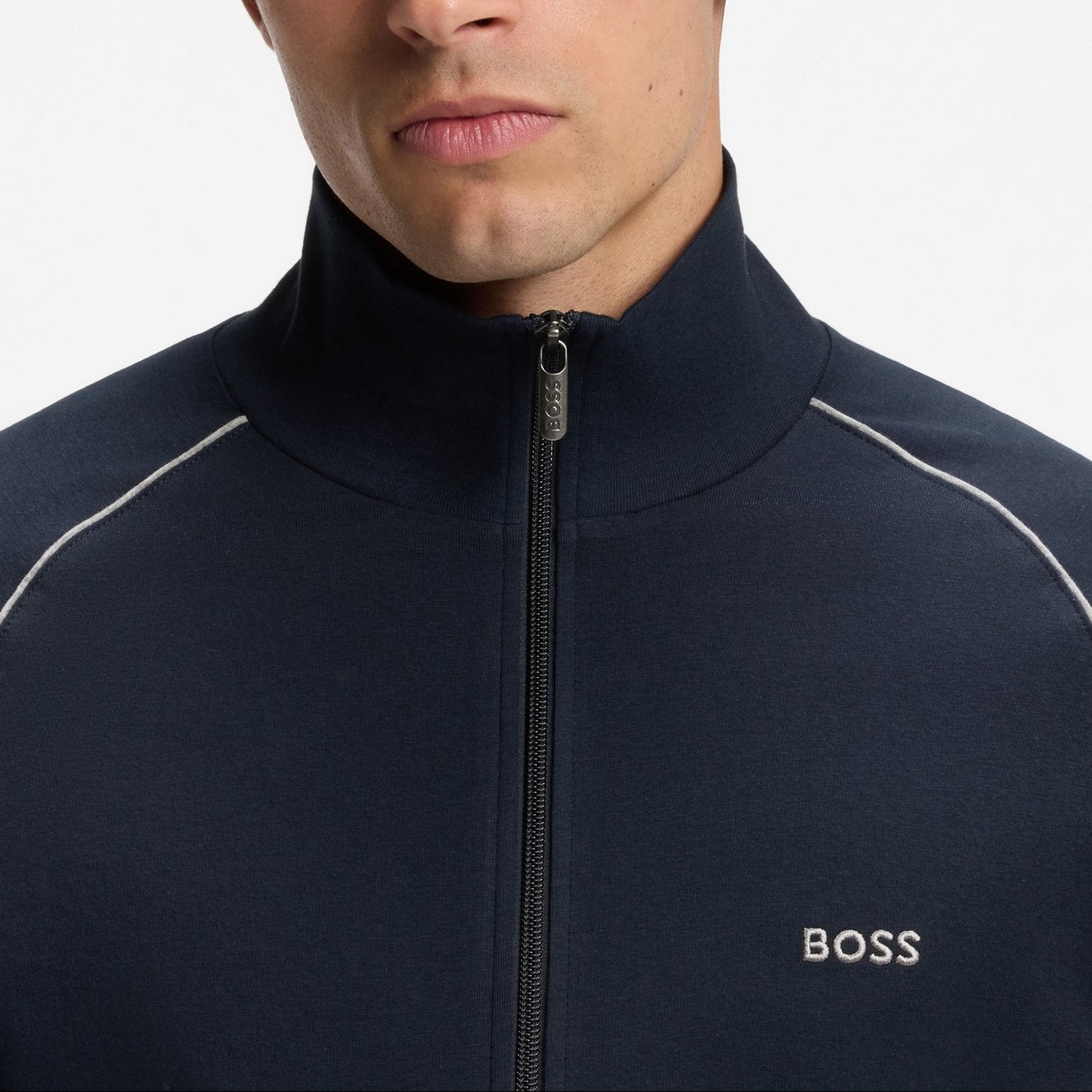 Man wearing a navy blue jacket with white accents, featuring the BOSS logo, on a plain background.