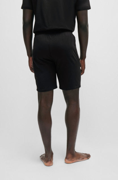Person wearing black shorts and a black shirt on a white background