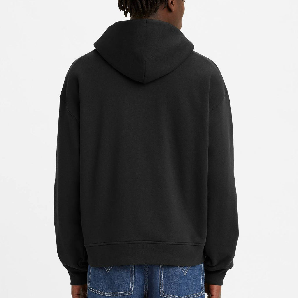 Person wearing a black hoodie and blue jeans on a white background