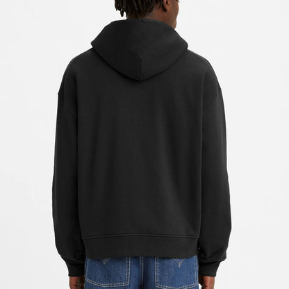 Person wearing a black hoodie and blue jeans on a white background