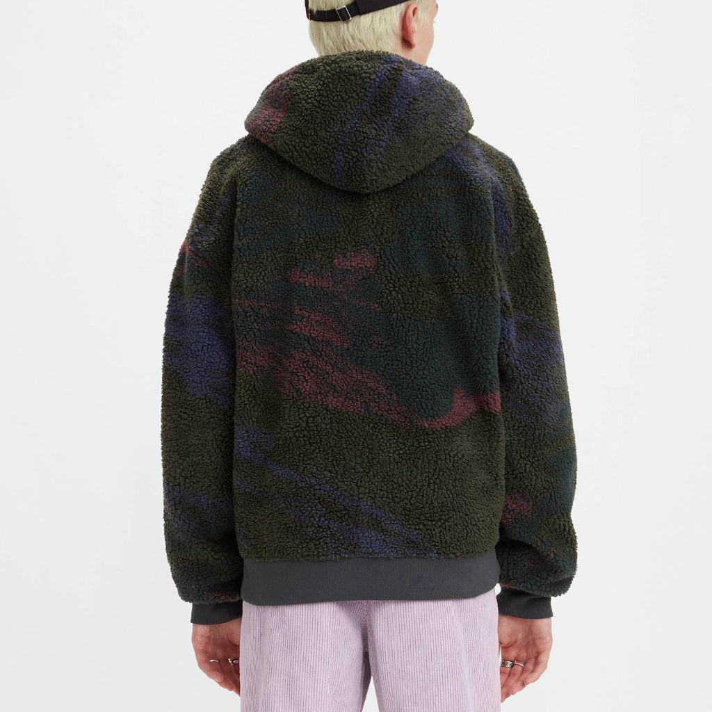 Person wearing a patterned hoodie and light purple pants on a white background