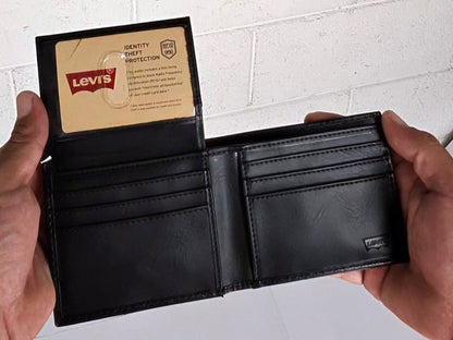 Black leather wallet held open by hands with a Levi's card inside, on a white brick wall background.