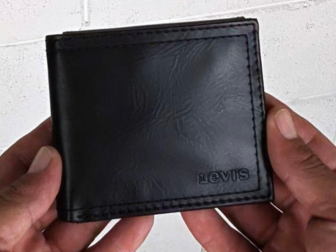 Black leather wallet with 'Levi's' branding held by hands against a light background